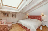 This cozy bedroom features a unique sloped ceiling with exposed wooden beams, creating a warm and inviting atmosphere.
