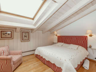 This cozy bedroom features a unique sloped ceiling with exposed wooden beams, creating a warm and inviting atmosphere.