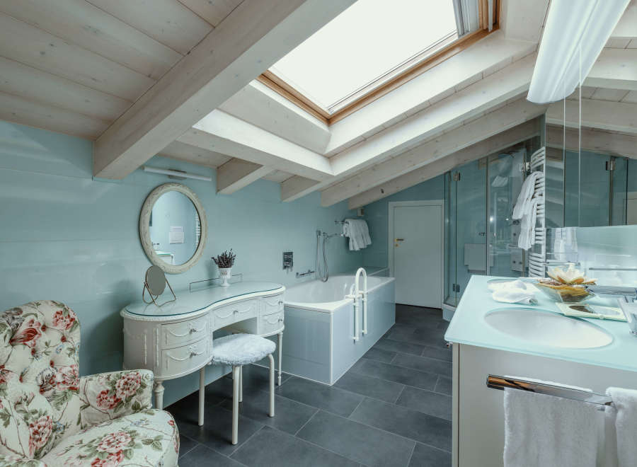 This luxurious bathroom features a unique design with a skylight and exposed wooden beams, creating a bright and airy atmosphere.