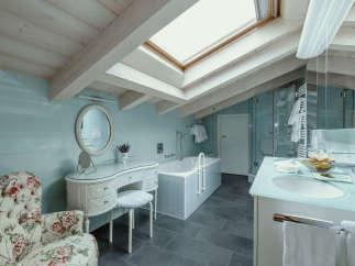 This luxurious bathroom features a unique design with a skylight and exposed wooden beams, creating a bright and airy atmosphere.