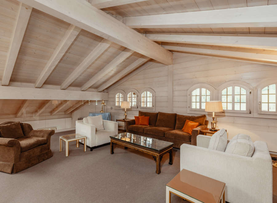 This stunning living room boasts a unique architectural design with a vaulted, wooden ceiling and exposed beams, creating a warm and inviting atmosphere.