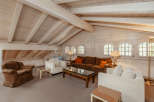 This stunning living room boasts a unique architectural design with a vaulted, wooden ceiling and exposed beams, creating a warm and inviting atmosphere.