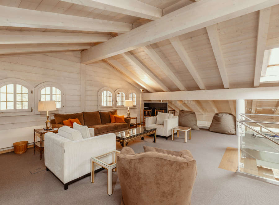 This stunning living space boasts a unique architectural design with exposed wooden beams and a vaulted ceiling, creating an airy and inviting atmosphere.