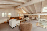 This stunning living space boasts a unique architectural design with exposed wooden beams and a vaulted ceiling, creating an airy and inviting atmosphere.