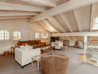 This stunning living space boasts a unique architectural design with exposed wooden beams and a vaulted ceiling, creating an airy and inviting atmosphere.