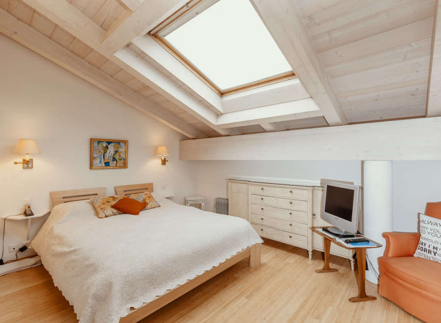 This charming bedroom features a unique sloped ceiling with exposed wooden beams, creating a cozy and inviting atmosphere.