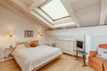 This charming bedroom features a unique sloped ceiling with exposed wooden beams, creating a cozy and inviting atmosphere.