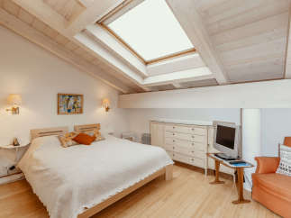 This charming bedroom features a unique sloped ceiling with exposed wooden beams, creating a cozy and inviting atmosphere.