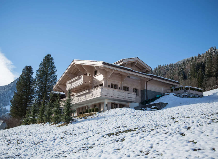 This stunning wooden chalet is nestled in a snowy mountain landscape, offering a serene retreat.