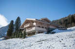This stunning wooden chalet is nestled in a snowy mountain landscape, offering a serene retreat.