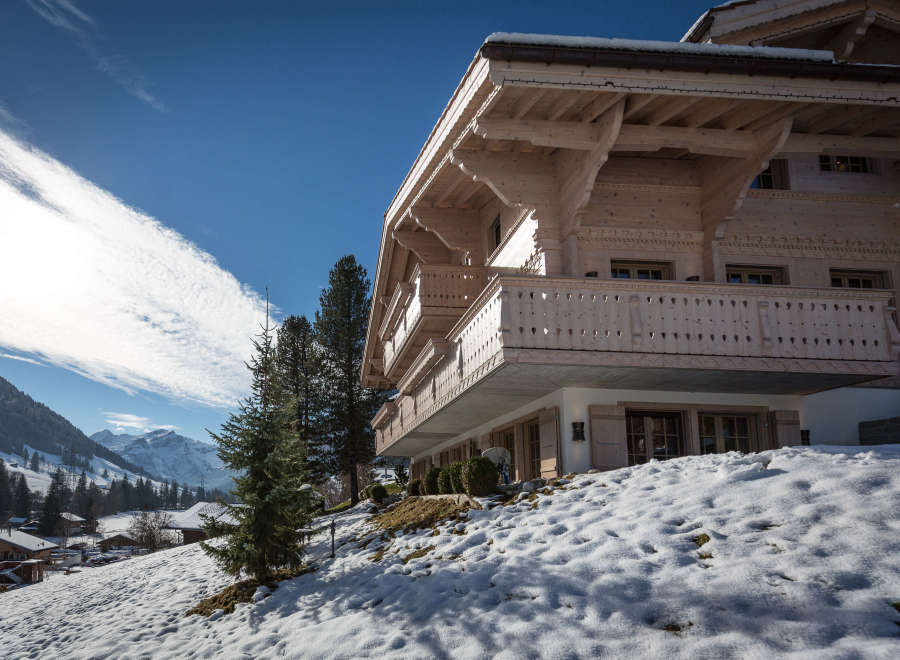 Experience the charm of a traditional wooden chalet nestled in a snowy landscape.