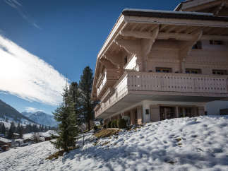 Experience the charm of a traditional wooden chalet nestled in a snowy landscape.