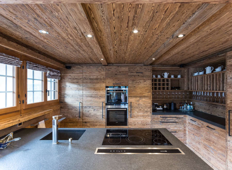 Experience rustic elegance in this stunning kitchen, featuring warm wood paneling and a sleek, modern countertop.