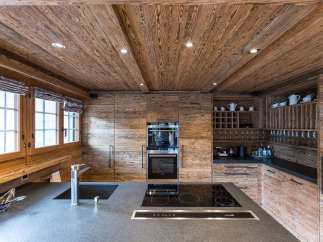 Experience rustic elegance in this stunning kitchen, featuring warm wood paneling and a sleek, modern countertop.