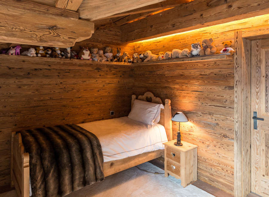 Cozy bedroom with wooden walls and ceiling, creating a warm and inviting atmosphere.