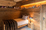 Cozy bedroom with wooden walls and ceiling, creating a warm and inviting atmosphere.