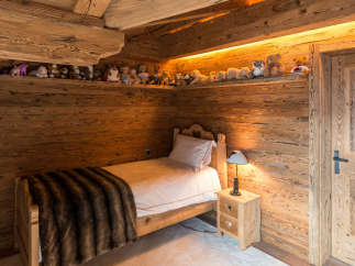 Cozy bedroom with wooden walls and ceiling, creating a warm and inviting atmosphere.
