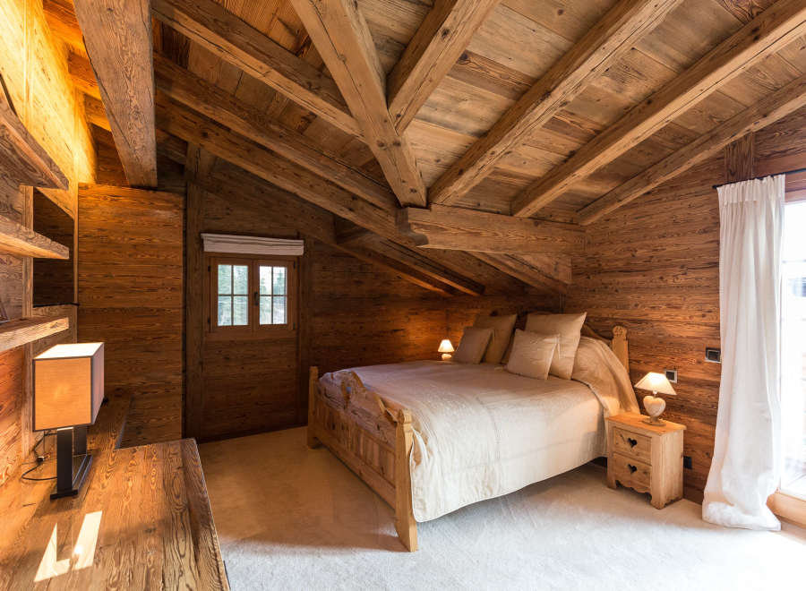 Experience rustic charm in this cozy bedroom, featuring a stunning wooden ceiling and walls.