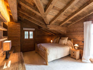 Experience rustic charm in this cozy bedroom, featuring a stunning wooden ceiling and walls.
