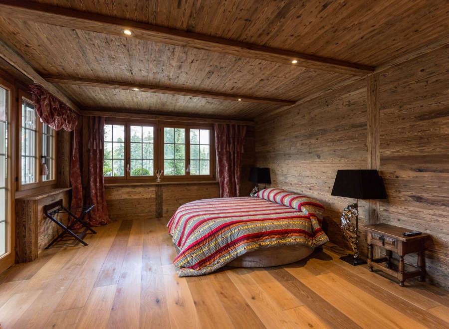 Experience rustic charm in this cozy bedroom, featuring warm wooden walls and flooring.