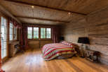 Experience rustic charm in this cozy bedroom, featuring warm wooden walls and flooring.