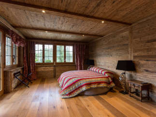 Experience rustic charm in this cozy bedroom, featuring warm wooden walls and flooring.