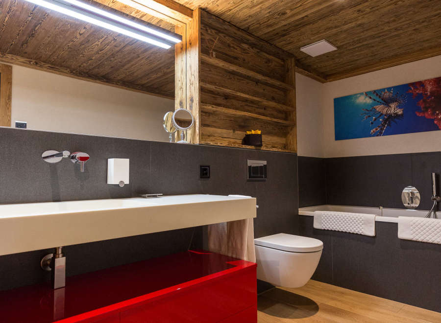 Experience luxury in this stunning bathroom featuring a striking red vanity and warm wooden accents.