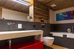 Experience luxury in this stunning bathroom featuring a striking red vanity and warm wooden accents.