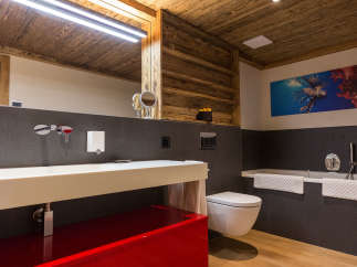 Experience luxury in this stunning bathroom featuring a striking red vanity and warm wooden accents.