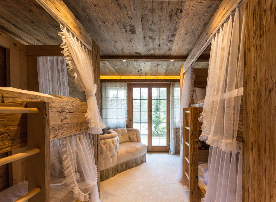 Step into a cozy bedroom retreat featuring rustic wooden bunk beds and a charming seating area.