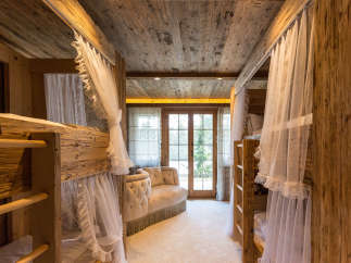 Step into a cozy bedroom retreat featuring rustic wooden bunk beds and a charming seating area.