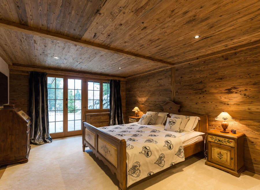 Experience the warmth of this cozy bedroom, featuring stunning wood paneling on the walls and ceiling.