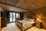 Experience the warmth of this cozy bedroom, featuring stunning wood paneling on the walls and ceiling.