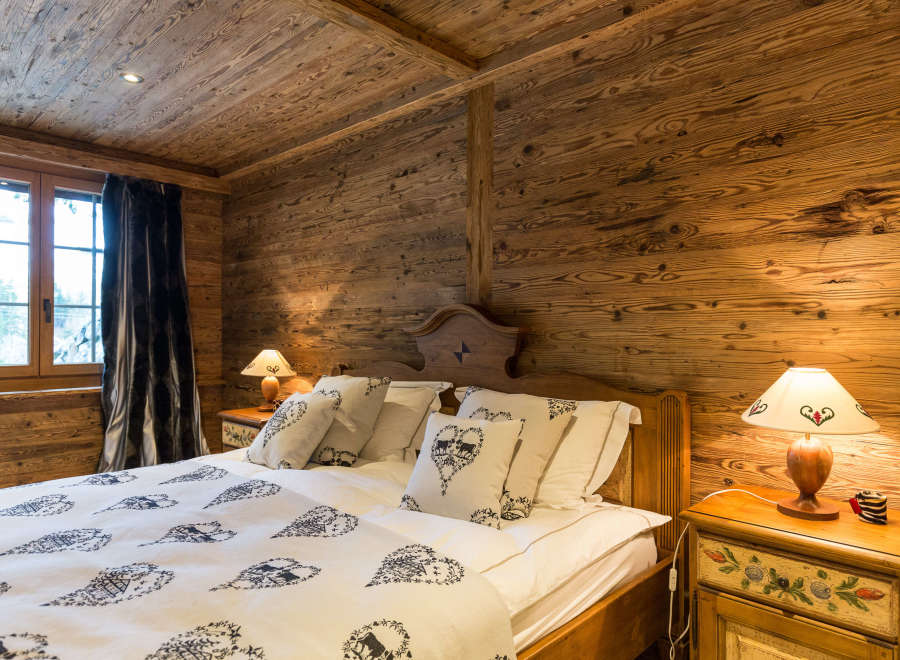 Experience rustic charm in this cozy bedroom, featuring warm wooden walls and a unique wooden ceiling.