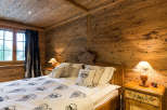 Experience rustic charm in this cozy bedroom, featuring warm wooden walls and a unique wooden ceiling.