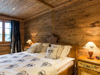 Experience rustic charm in this cozy bedroom, featuring warm wooden walls and a unique wooden ceiling.