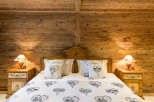 Cozy bedroom with rustic wooden walls and a charming bed.