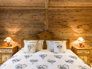 Cozy bedroom with rustic wooden walls and a charming bed.