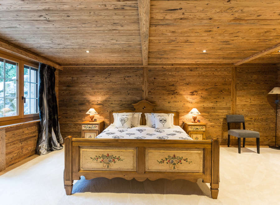 Step into a cozy bedroom retreat with rustic wooden walls and ceiling.