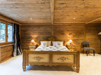 Step into a cozy bedroom retreat with rustic wooden walls and ceiling.
