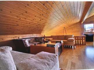 This cozy living space features a stunning wooden ceiling and warm wooden floors, creating a rustic and inviting atmosphere.