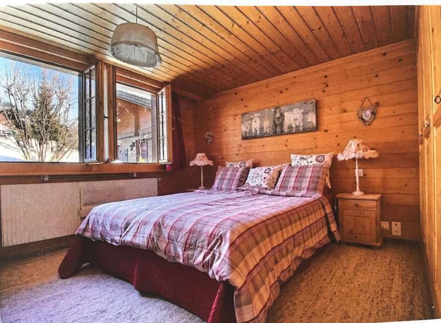 Cozy bedroom with wooden walls and ceiling, creating a warm and inviting atmosphere.