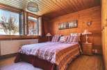 Cozy bedroom with wooden walls and ceiling, creating a warm and inviting atmosphere.