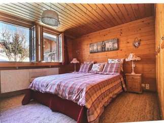 Cozy bedroom with wooden walls and ceiling, creating a warm and inviting atmosphere.