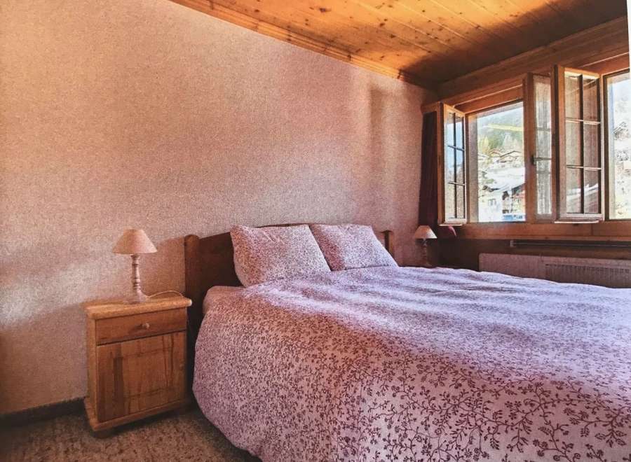 Cozy bedroom with a rustic wooden ceiling and a charming floral bedspread.