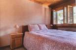 Cozy bedroom with a rustic wooden ceiling and a charming floral bedspread.