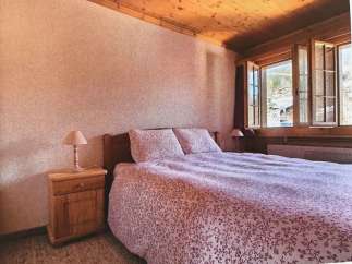 Cozy bedroom with a rustic wooden ceiling and a charming floral bedspread.