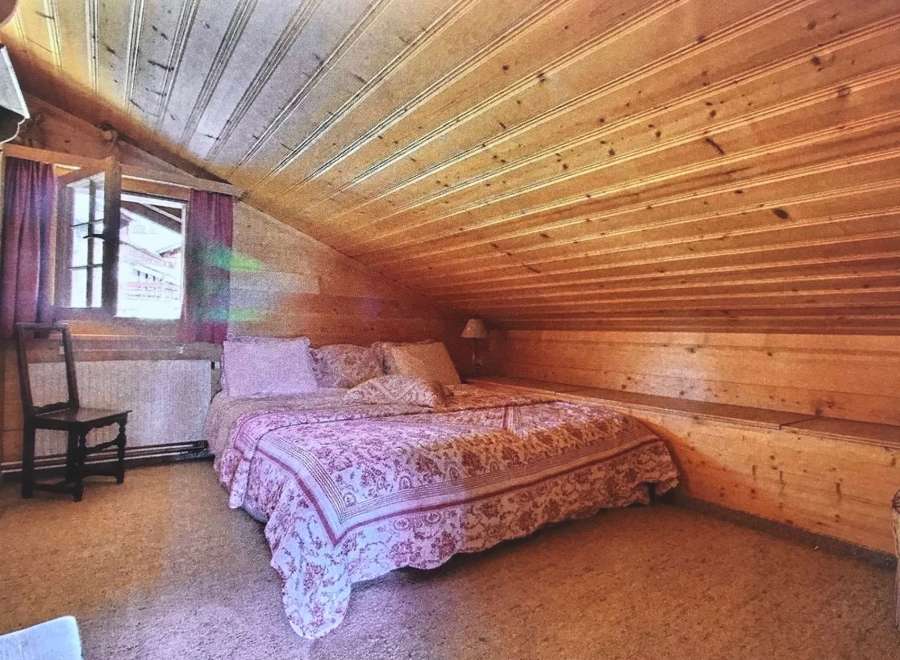 Cozy bedroom with a unique wooden sloped ceiling.