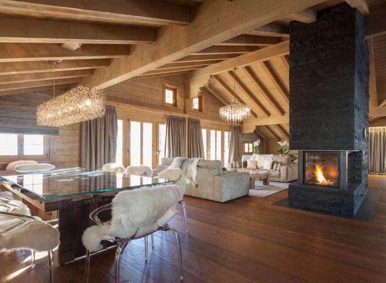 Experience luxury living in this stunning chalet, featuring a cozy fireplace and elegant chandeliers.