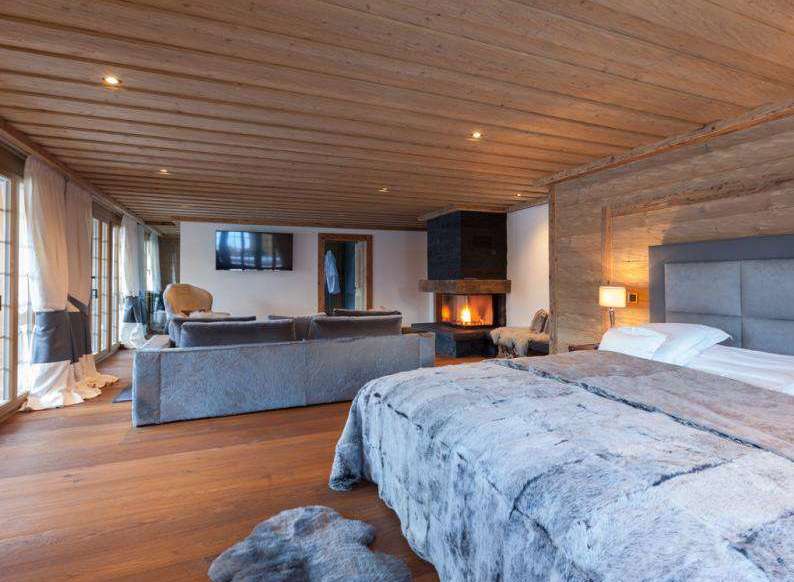 Experience luxury in this stunning bedroom featuring a cozy fireplace and a plush, inviting bed.